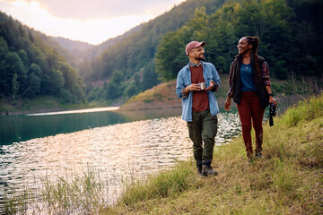Happy couple enjoys in walk by river while camping in nature.