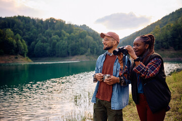 Happy multiracial couple exploring nature with binoculars.