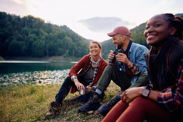 Group of young happy friends relaxing by lake in nature.