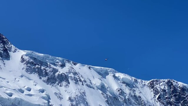 A helicopter flies by the Akkem Wall, Altai, Russia. An excursion helicopter with tourists flies near Belukha Mountain. Beautiful view of the mountains. Amazing panorama of hills, rocks, ridges