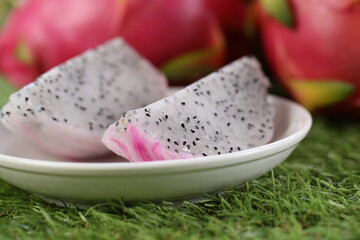 Dragon fruit on green grass with natural bokeh. Asian read fruit with jelly white sweet fruit.