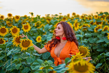 Naklejka premium portrait of a beautiful woman near a field of sunflowers on a sunny day at sunset.