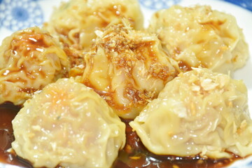 steamed Chinese dumpling filling mashed pork and shrimp topping crispy fried garlic or dim sum dipping soy sauce on plate isolated in white background