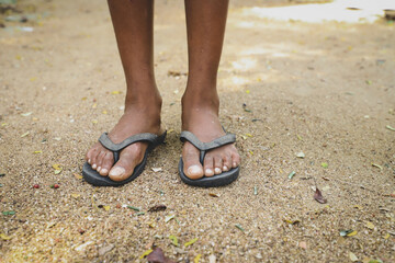 Feet of poor kid wearing dirty shoes standing