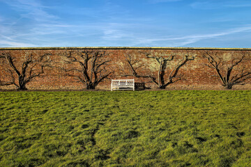 Wall in the countryside with a sole bench against a bright blue sky