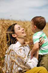 Happy mother and son are playing in a wheat field in Ukraine 