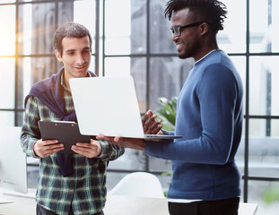 young business men standing together holding a laptop, discussing business