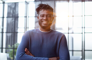 Portrait of a happy confident young african american businessman standing with his arms crossed looking at camera