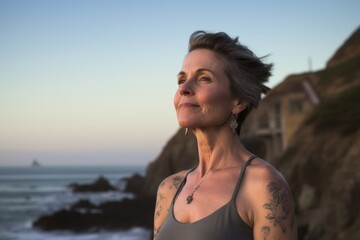 Obraz premium Three-quarter studio portrait photography of a satisfied mature woman wearing a intimate apparel against a scenic ocean cliff background. With generative AI technology