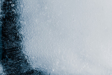 Ice texture background with air bubbles. The textured crunchy piece of ice is on black background.