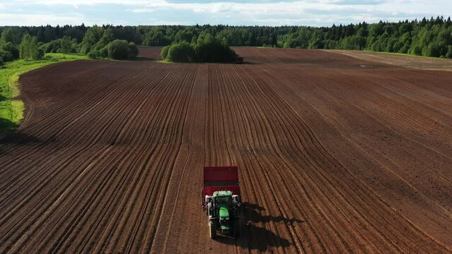 Drone takes off over arable, tractor with potato planter plants potato in field