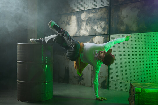 Male break dancer performing on loft stage in green neon light
