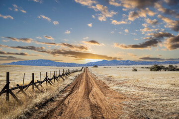 A lonely dirt road heading into the sunset through the grasslands along the border between the United States and Mexico in Arizona
