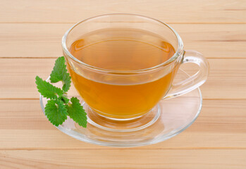 Tea mint in glass cup with mint leaves on wooden table background.