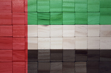 colorful painted big national flag of united arab emirates on a wooden cubes texture.