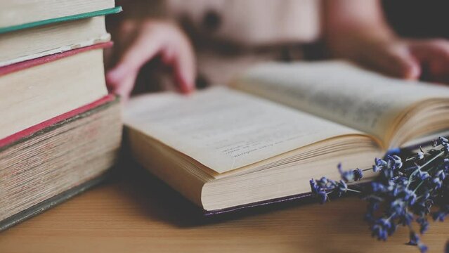 a girl in a vintage dress sits at a table and reads a book. Girl turning the pages, reading a novel in an old library