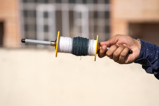 man holding spool charkhi of string with glass covering showing fighting kites flown on sankranti uttarayan independence day in Delhi