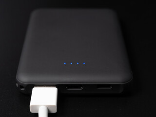 Power bank for charging mobile devices on a black background. Smartphone charger with power supply....