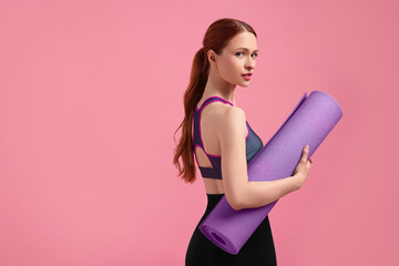 Woman in sportswear with fitness mat on pink background, space for text