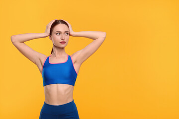 Fototapeta na wymiar Young woman wearing sportswear on yellow background, space for text