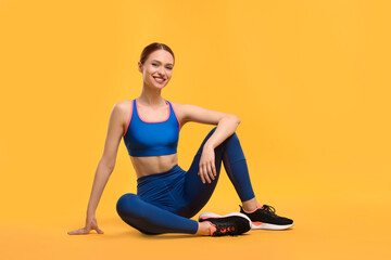 Young woman wearing sportswear on yellow background
