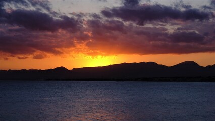 sun setting over the seaside and mountains