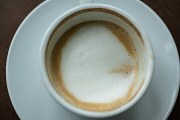 Top view white cup of hot coffee latte art on wood background in restaurant.