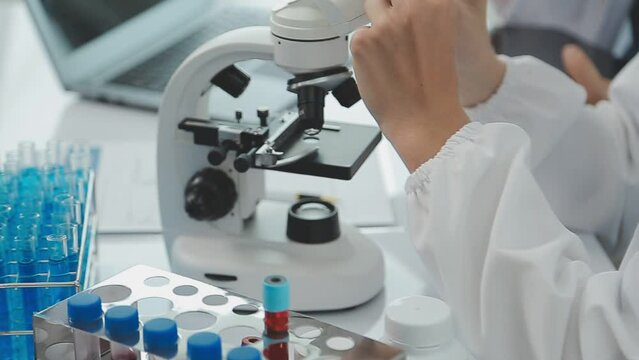 Health care researchers working in life science laboratory. Young female research scientist and senior male supervisor preparing and analyzing microscope slides in research lab.