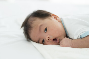 Obraz na płótnie Canvas Newborn baby sleeping on blanket on white bed. Infant lying on white bed. Asian newborn baby sleeping in prone position. Asian infant