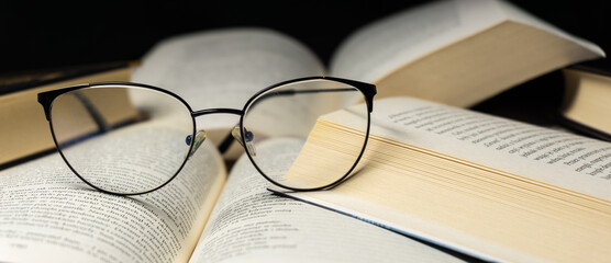 New paperback books, diary, fanned pages on wooden desk table and grunge background Daylight. Books stacking. Back to school. Copy Space. Education background, Reading background, glasses on book.
