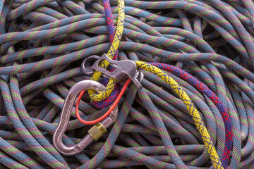 atc style belay device with double ropes threaded through, on a background of flaked climbing rope