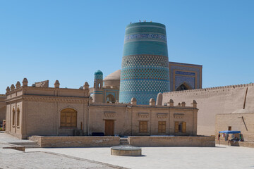 Ancient Kalta-Minor minaret in urban landscape on a sunny day. Old city of Ichan-Kala, Khiva