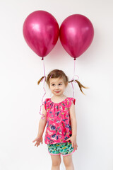 Fototapeta na wymiar cute girl with two purple balloons tied to pigtails on a white background. Happy childhood.
