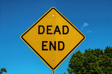 Yellow Dead End Sign against blue sky and some summer trees