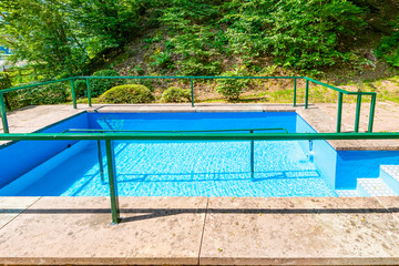 Small pool in a natural water spring to cool feet of walkers, pedestrian hiking trail around Lake Stausee Bitburg, wild plant foliage in background, sunny summer day in Germany