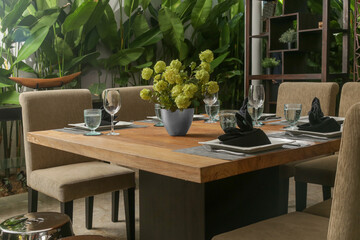 Massive wooden dining table with beautiful flower centerpiece on the balcony