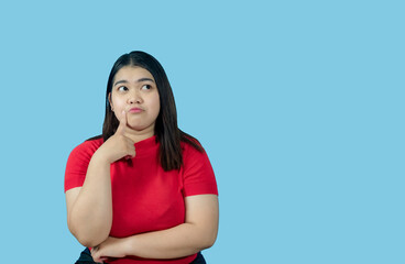 Portrait girl young woman asian chubby fat cute beautiful pretty one person wearing a red shirt is sitting, looking, and thinking idea  suspiciously and seriously  isolated blue background