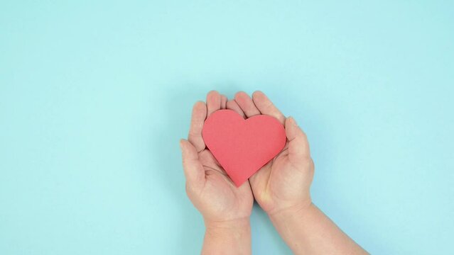 Hands holding red heart, love and emotion concept, good hearted person, help and charity