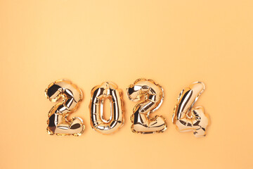 2024 glowing inflatable balloons on a golden background with copy space. Monochrome New Year festive concept.