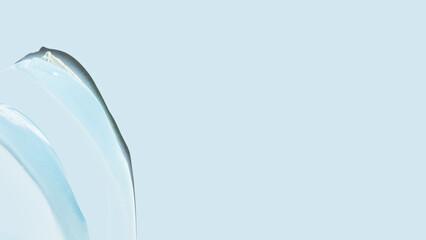 Drops and smears of a transparent gel or serum on a blue background. Banner with empty space for advertising.