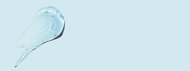 Drops and smears of a transparent gel or serum on a blue background. Banner with empty space for advertising.