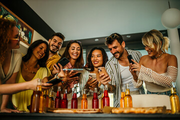 Friends gather in the living room, taking pictures of a pizza for social media.