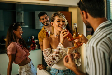 A group of friends engage in lively conversation, having food and drinks, sharing a joke, and laughing together.