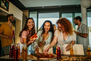 A group of friends engage in lively conversation, having food and drinks, sharing a joke, and laughing together.