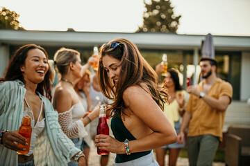 A group of people raise their cocktail bottles, cheering and celebrating the fun moments they've shared throughout the party.