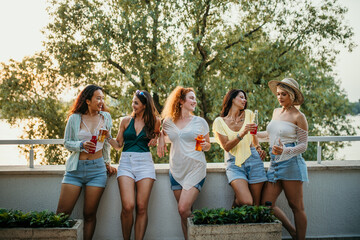 Multiethnic female friends make a reunion at the house balcony, toasting and having fun
