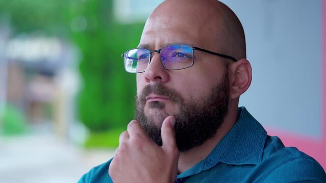 Contemplative man thinking deeply with hand in chin, touching beard, while pondering decision. Male person questioning the meaning of life