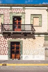 Old classic facade with tiles of an antique building with balcony in sunny Atlixco in Puebla, Mexico. 