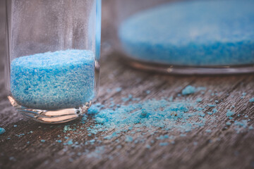 blue copper sulphate granules in glass floors - insulated close-up on wood background - obrazy, fototapety, plakaty