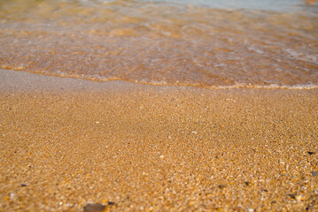 Fototapeta na wymiar Golden sand at the beach, with soft touch of a calm waves